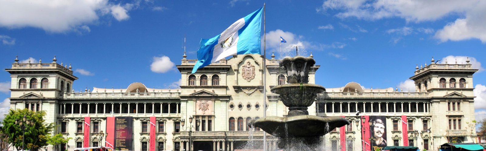 The fountain of Constitution Plaza lined with locals on a sunny day, Guatemala City in Guatemala