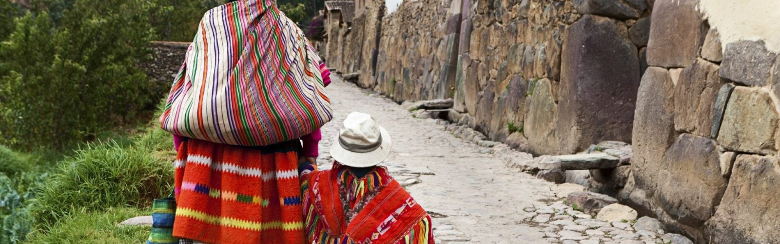 A mother and son walking along an old street in Cuzco.