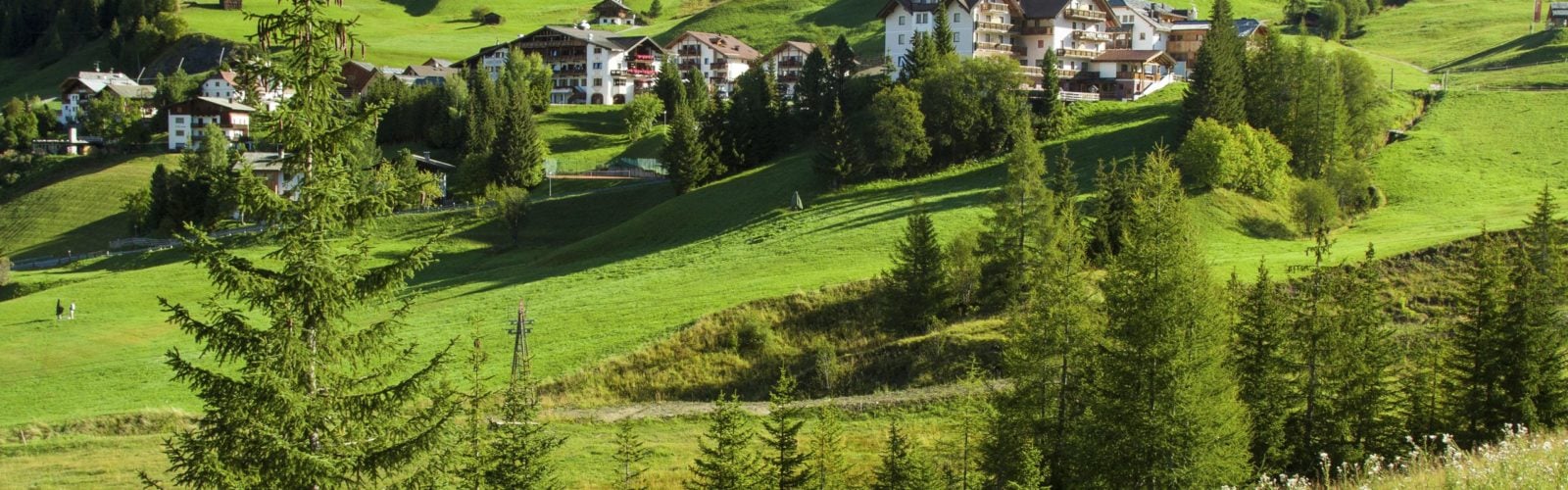 Buildings nestled in the rolling green hills in the foothills of the Dolomites, Italy