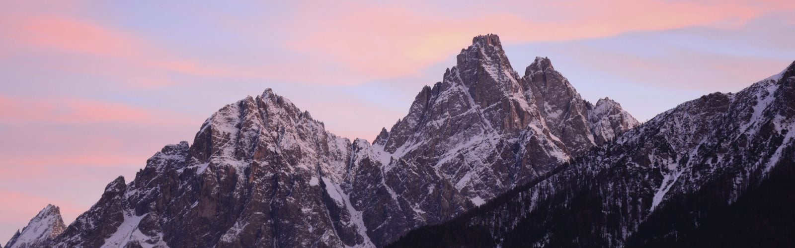 Snow-capped peaks of the Dolomites, Italy, drenched in a pink sunset