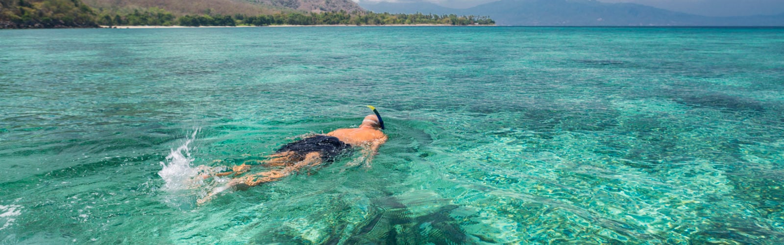 Man snorkeling in crystal blue waters, Komodo Islands, Indonesia