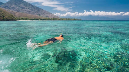 Man snorkeling in crystal blue waters, Komodo Islands, Indonesia