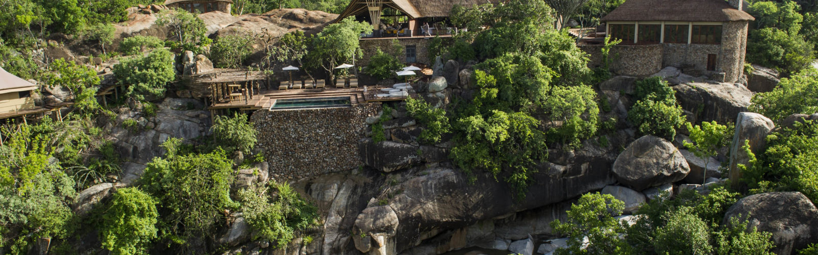 View of Legendary Mwiba Lodge set upon the rocks among the trees above the river, Mwiba Wildlife Reserve Tanzania