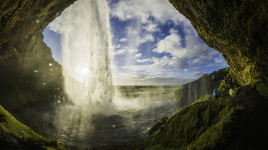 Waterfall tumbling into river above cavern mouth Seljalandsfoss Iceland