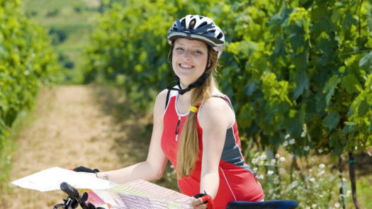Woman cycling through vineyards, Mendoza, Argentina