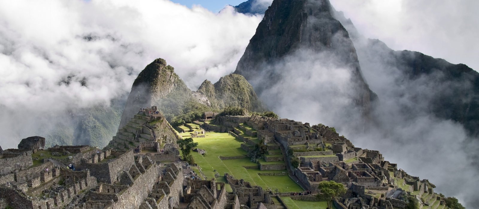 Panoramic view of Machu Picchu emerging through the clouds on a sunny day