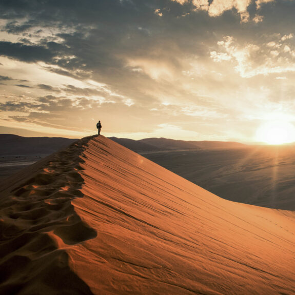 Dramatic sunrise in the Namibian desert with person standing and overlooking the great plains