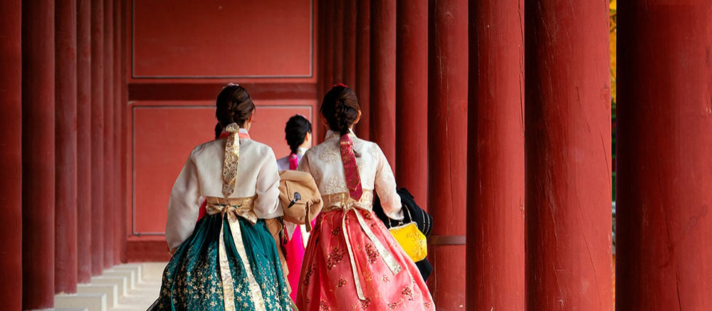Asian girls in hanbok dress walking between the red pillar of Autumn Leaves Park
