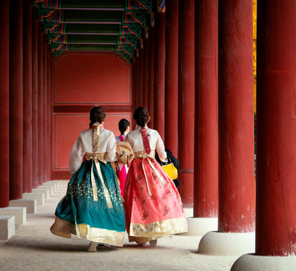 Asian girls in hanbok dress walking between the red pillar of Autumn Leaves Park