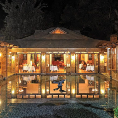 View of the dining room of Arusha Coffee Lodge from across the fountain at night, Arusha Tanzania