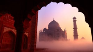 Taj Mahal in the warm pink and yellows of sunrise on a foggy morning