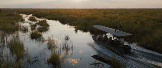 A boat drives through the Okavanga delta during sunset