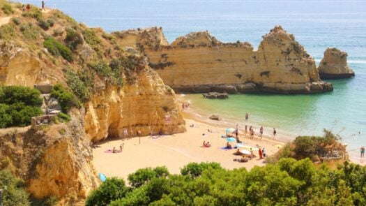 A sun-kissed Algarve beach with people enjoying the sand and water.