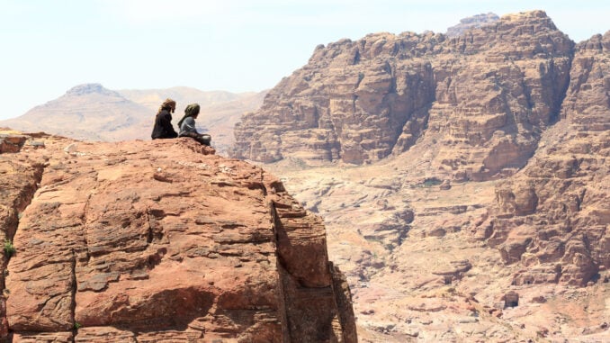 Bedouins sitting on rock at High place of sacrifice in ancient city of Petra in Jordan