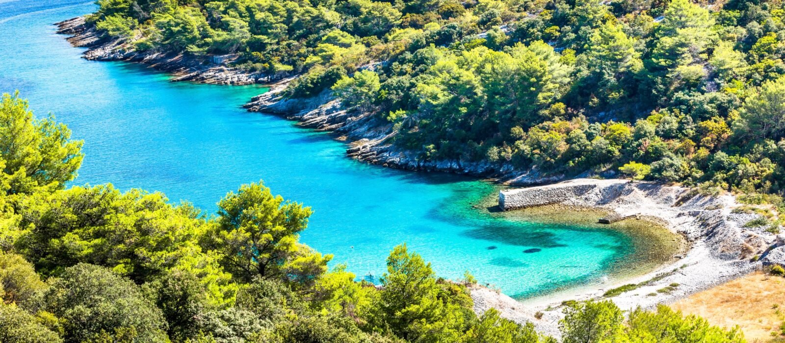 Crystal blue waters of the Island of Brac, Croatia, with forest lined rugged coastline