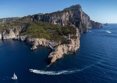 aerial view of a sailboat, a motorboat and a lighthouse on the coast of Capri